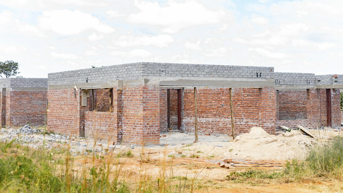 Casa térrea em construção com paredes de tijolos vermelhos e laje de concreto cinza