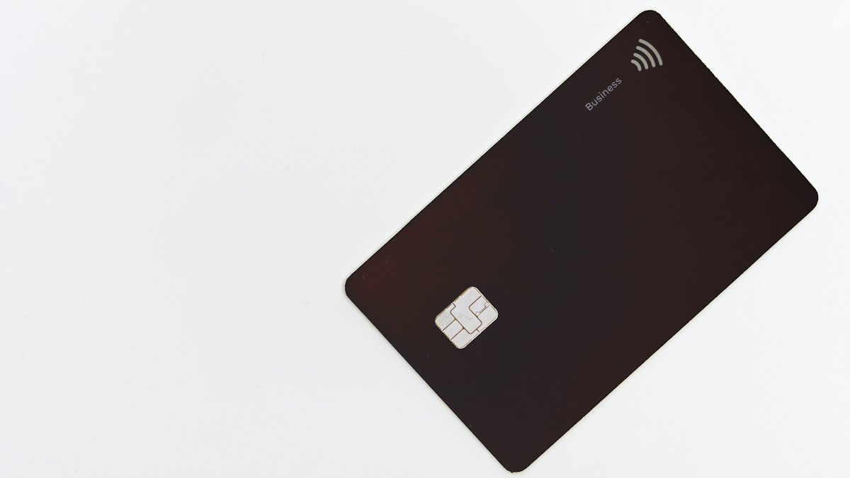 Cartão bancário preto com chip deitado sobre uma superfície branca lisa